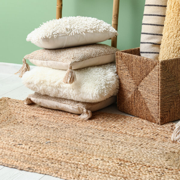 Carpets, cushions and wicker rug near green wall