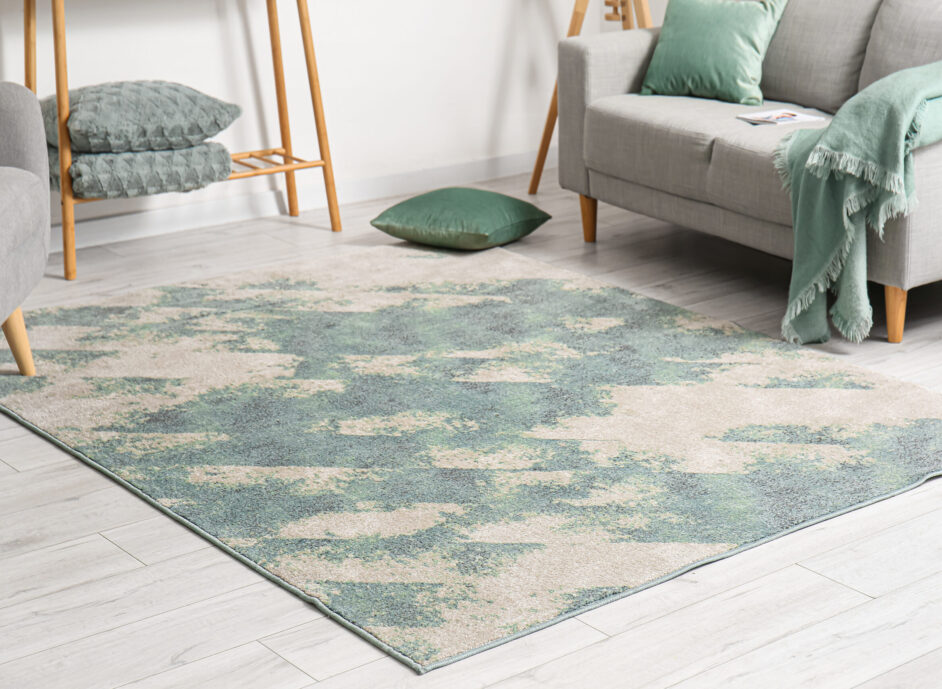 Soft stylish carpet on grey wooden floor in living room interior