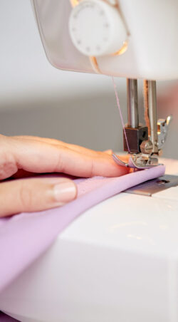 needlework and tailoring concept - sewing machine presser foot stitching fabric